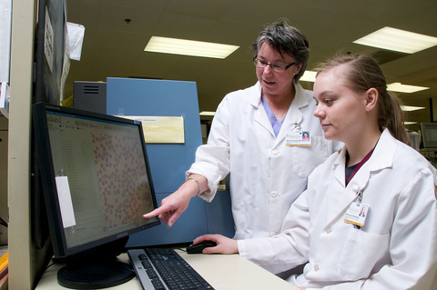 An instructor showing a student something on a computer display